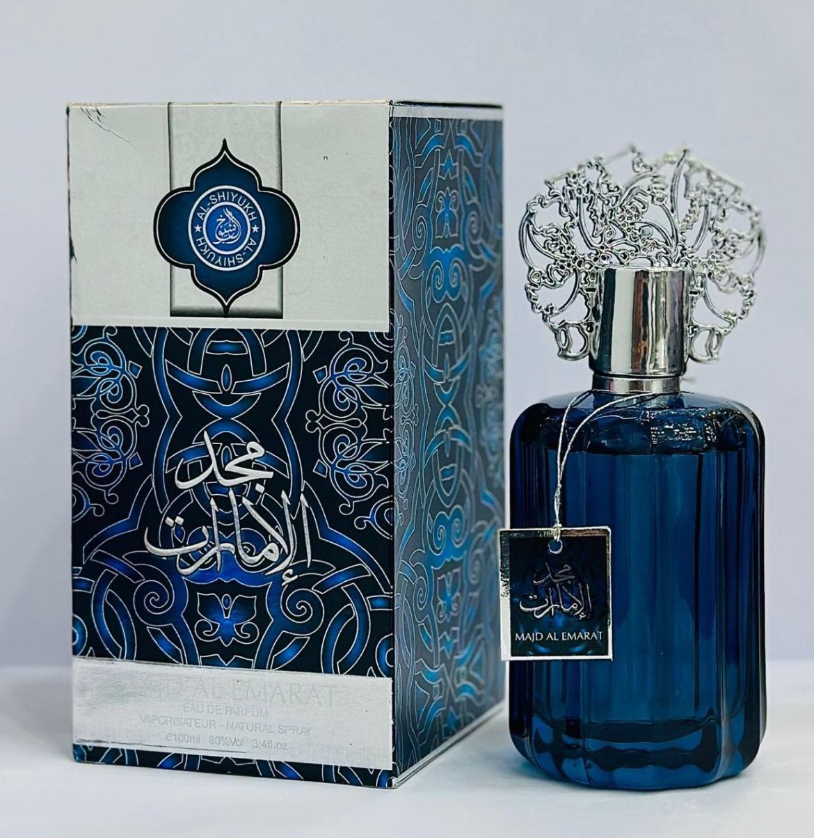 Majd Al-Emarat perfume in deep blue and silver bottle, crafted with high-quality fragrance oils, long-lasting Arabic scent for men by Innopick.